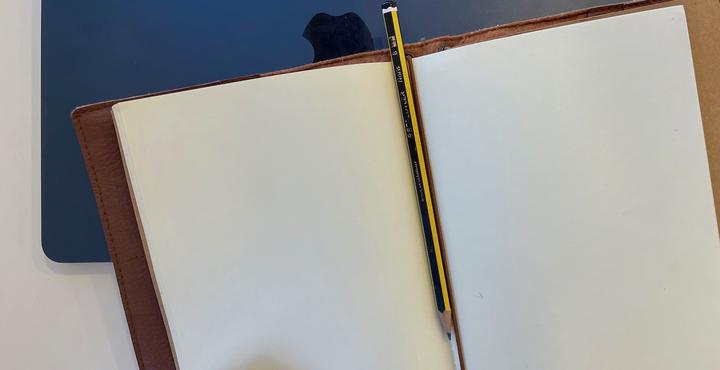 photo of an open notebook with a pencil between the pages